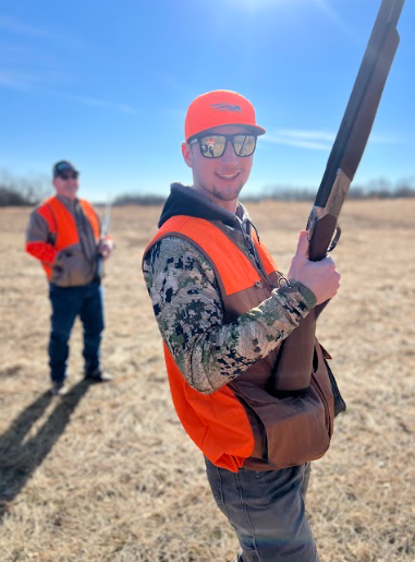 New hunter learning to use a hunting rifle in the field with his hunting instructor